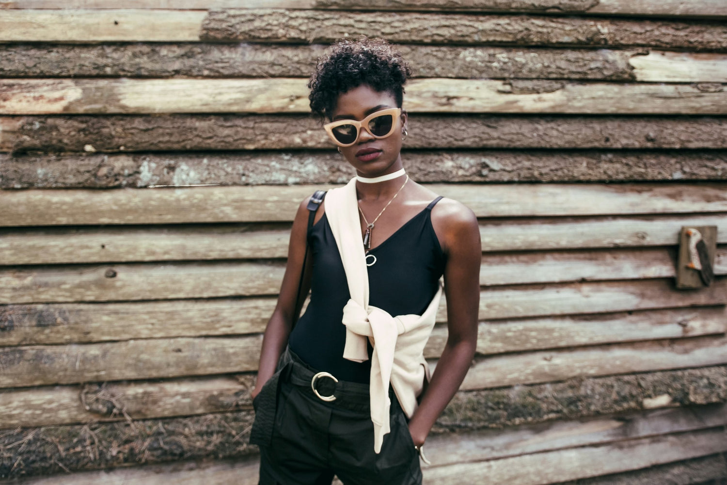 black girl standing in front of wooden building with sunglasses on